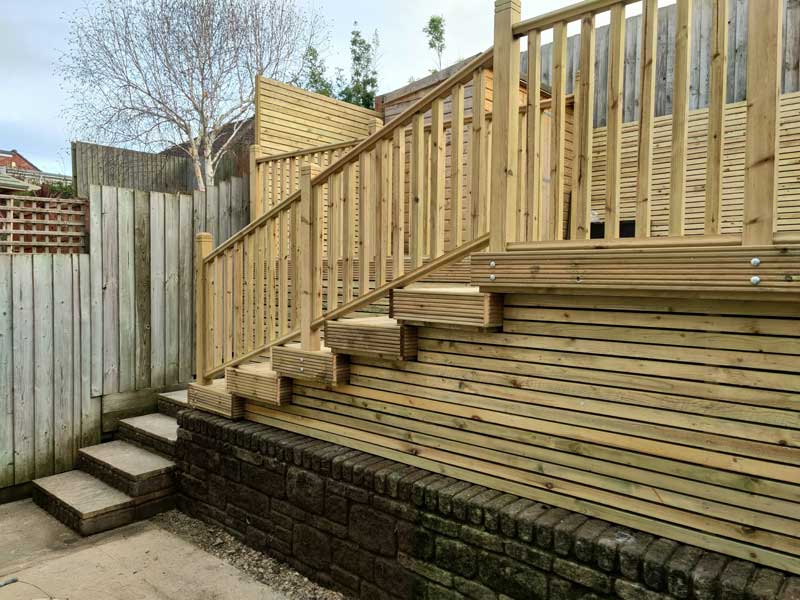 stone steps leading to a decking area at head height - a great landscaping idea for a small garden which employs the art of hide and reveal