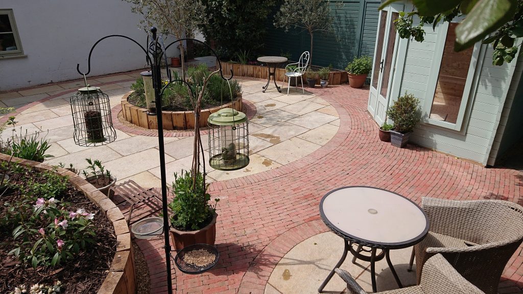 complex patio with circular areas of paving slabs joined by areas of brick pavers
