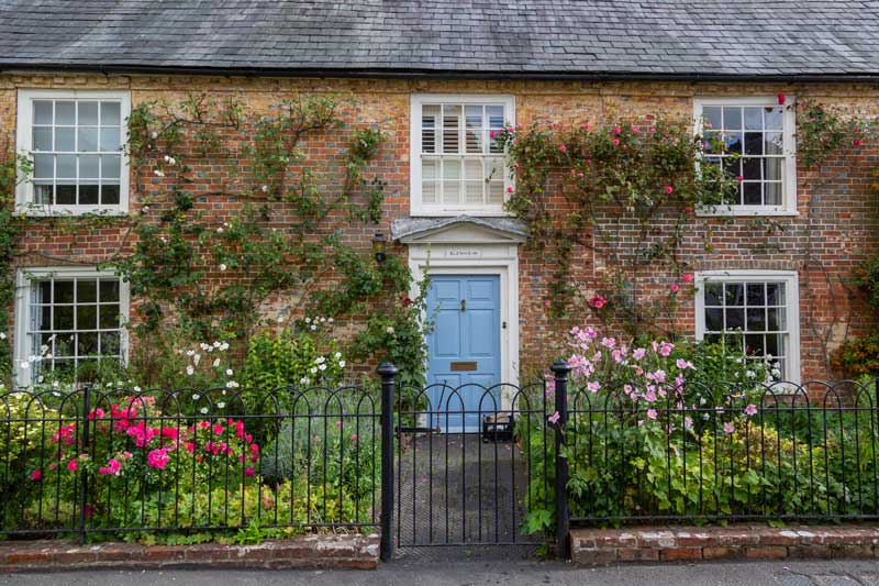 english country cottage with sash windows and colourfully planted front garden