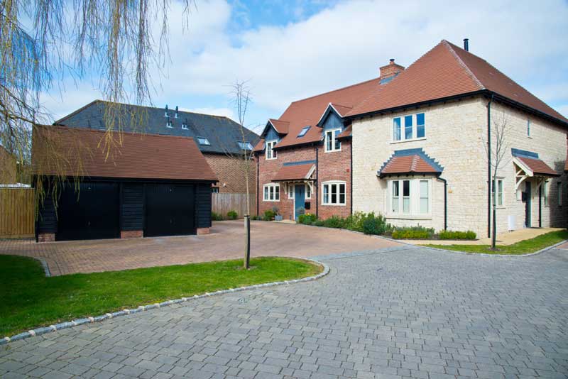 newbuild property with elegantly designed driveway and cart shed