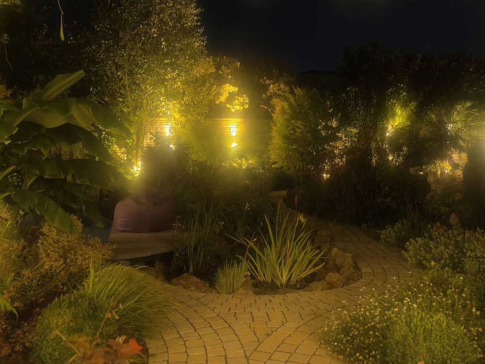 night time shot of a garden paved with limestone setts and beautifully planted with aromatic plants