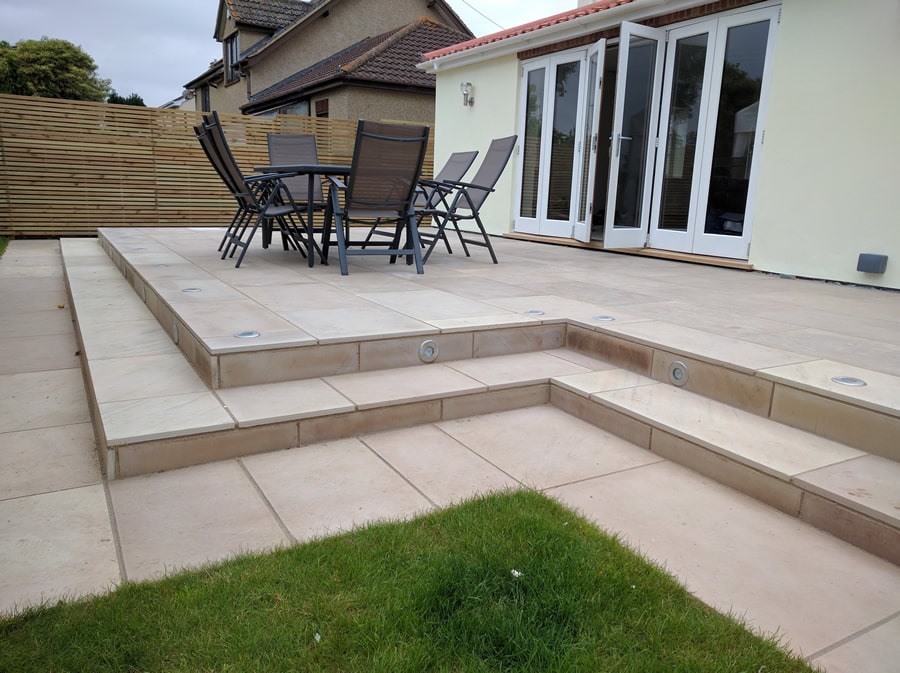 cream coloured patio with 3 steps down onto a natural grass lawn