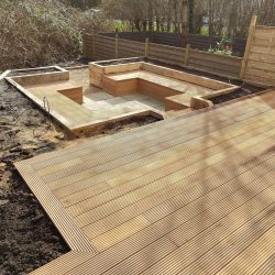 decking area surrounded by planting space and leading on to a sunken patio