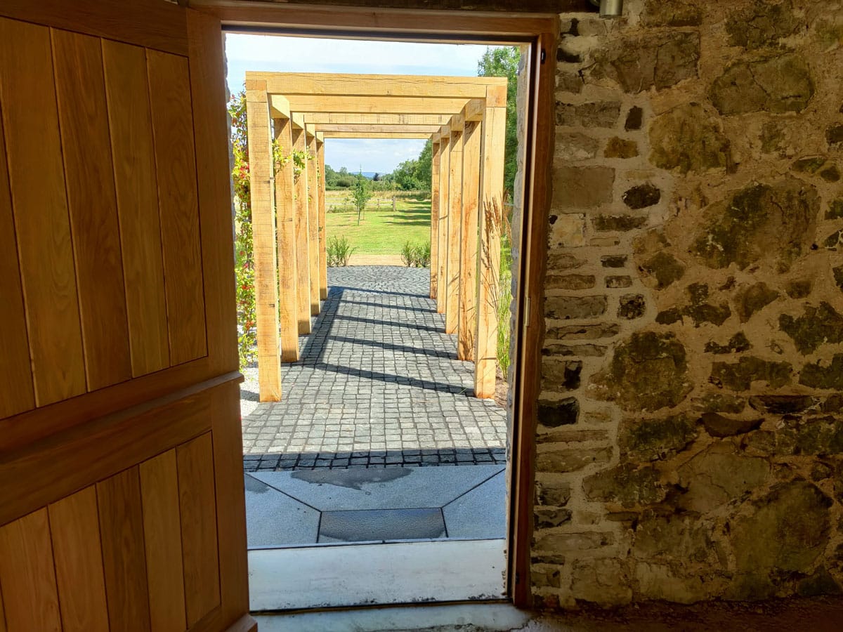 view through a door to small tree framed by timber pergola and walkway