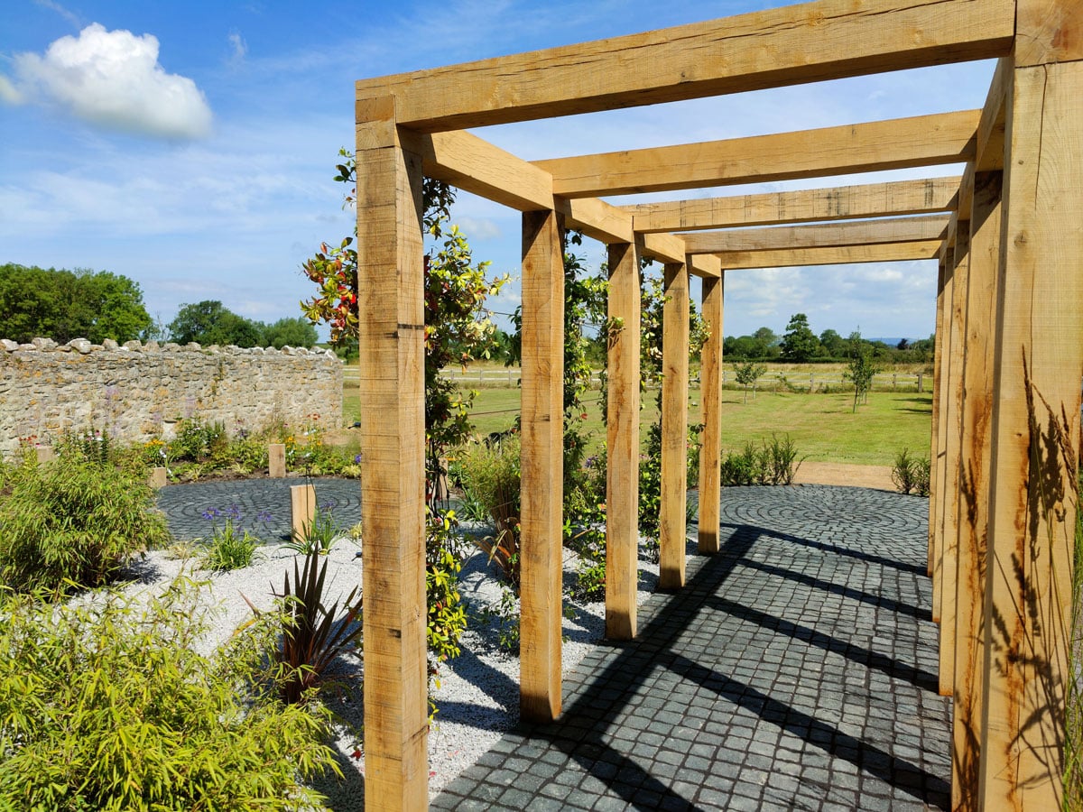 timber pergola to right of image with limestone setts as flooring