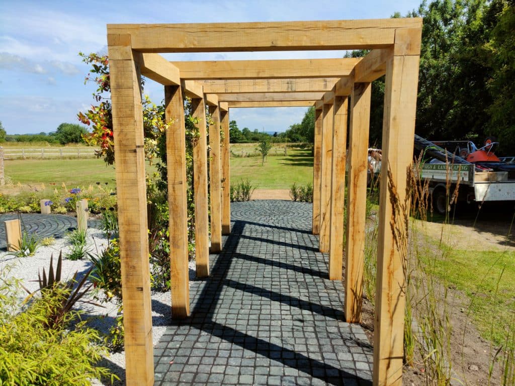 view through long narrow wooden pergola towards open countryside