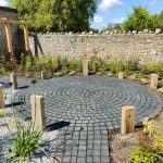 circular garden feature made with limestone setts and framed by low upright timbers similar to a henge