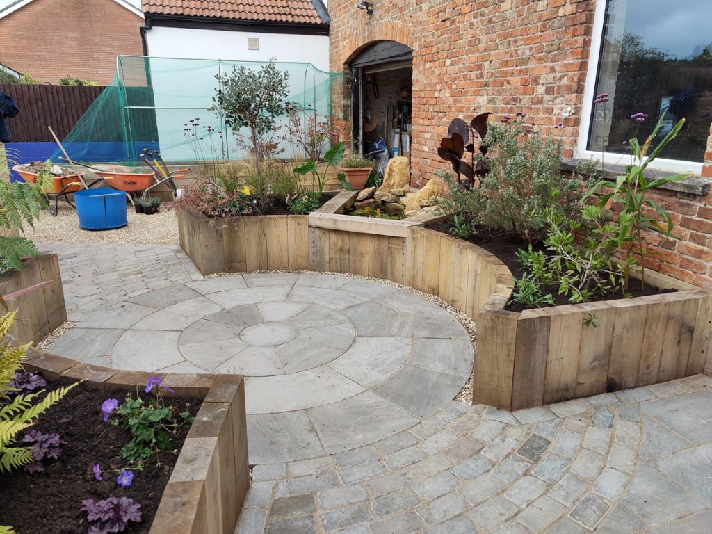 raised bed made using vertical timbers and with a small water feature built into it