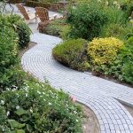 meandering limestone path leading through mature herbaceous planting to a beautiful outdoor seating area