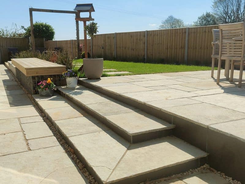 two garden terraces on different levels are connected by natural limestone steps
