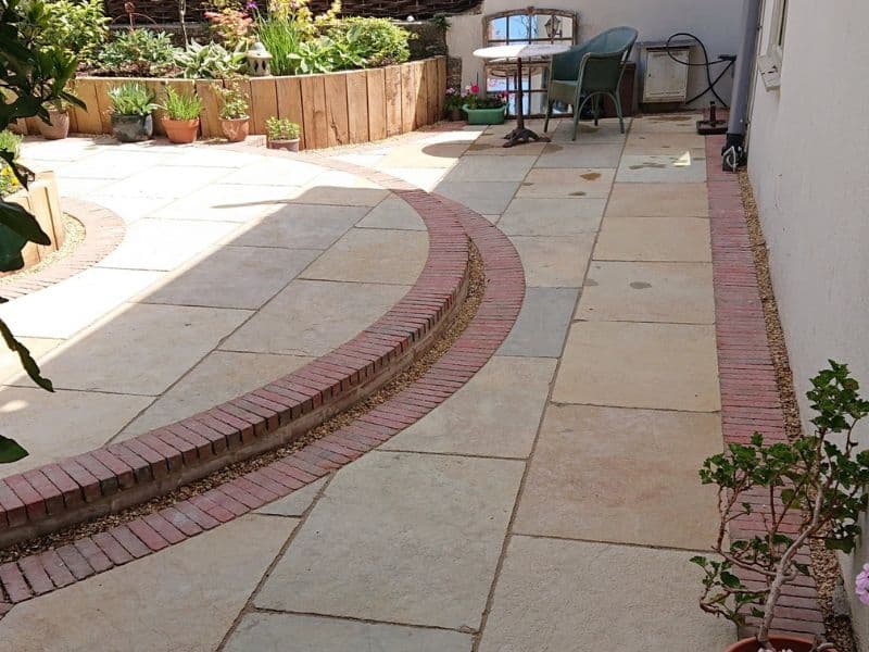 natural limestone patio with a pinkish tinge to the stone is accentuated by the use of red clay pavers used as edgings and inserts